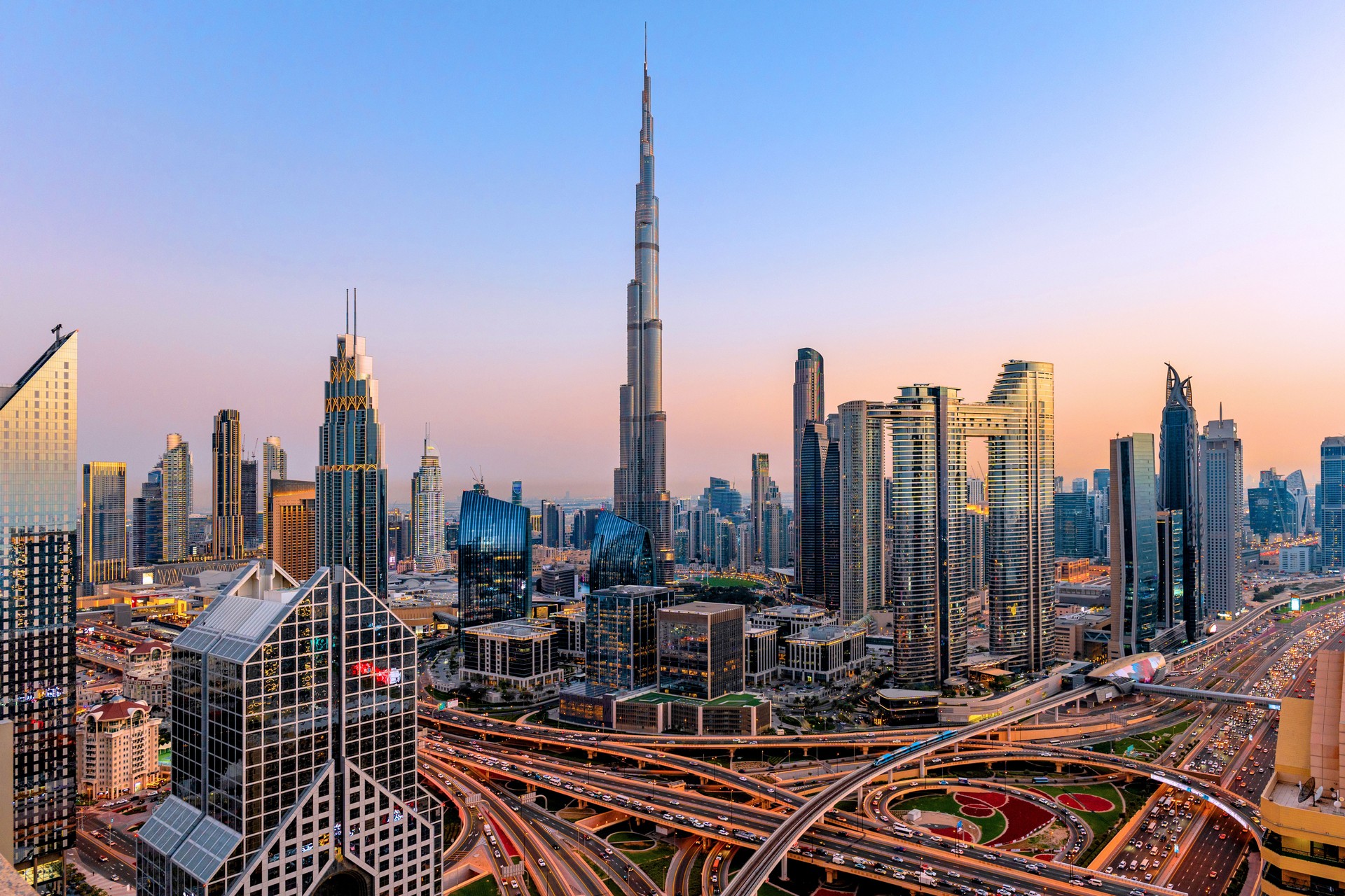 Aerial cityscape of Dubai at sunset with modern skyscrapers, illuminated highways, busy traffic and dense urban development. Dubai rapidly growing metropolis with futuristic skyline and vibrant life